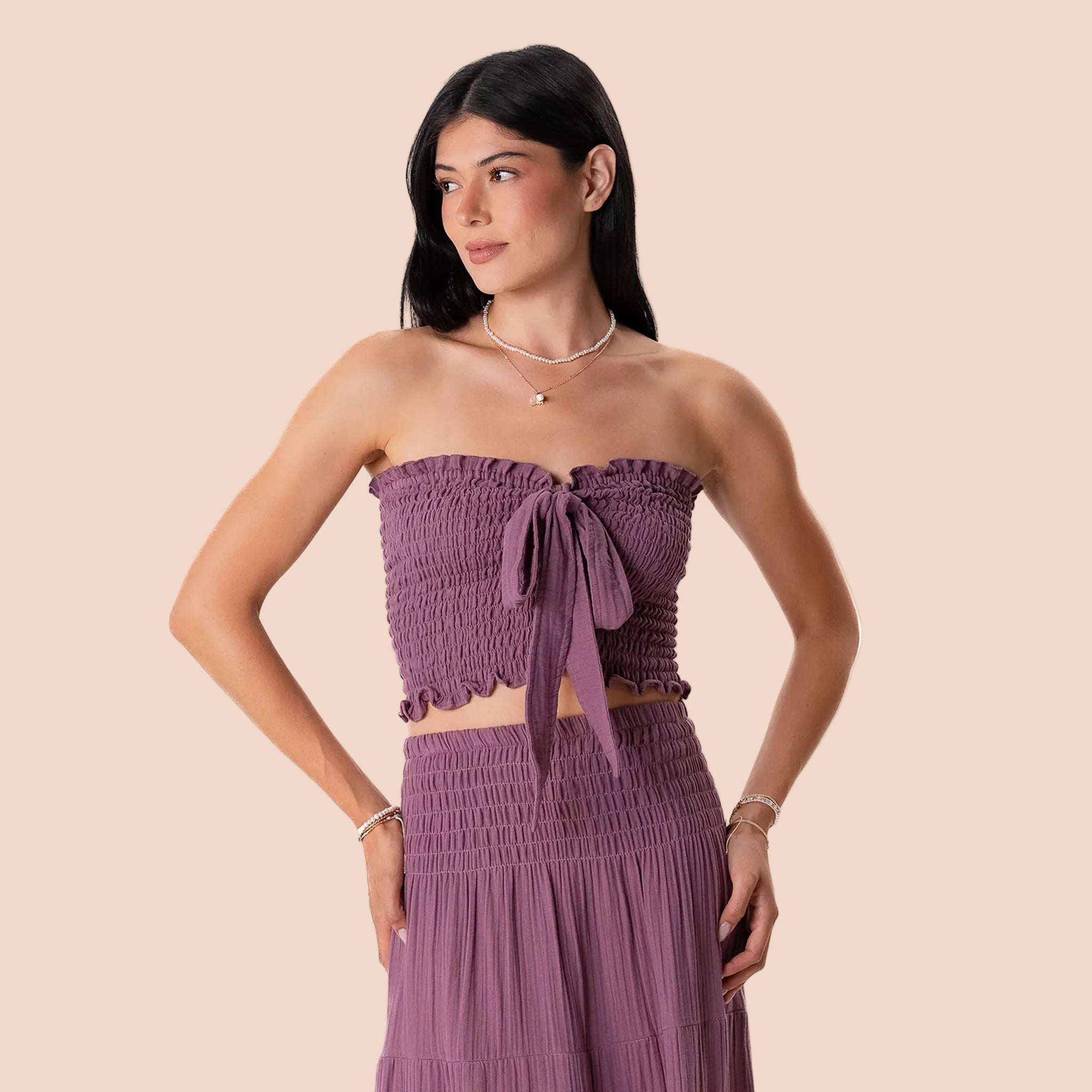 Woman wearing a purple strapless top and skirt set on a white background
