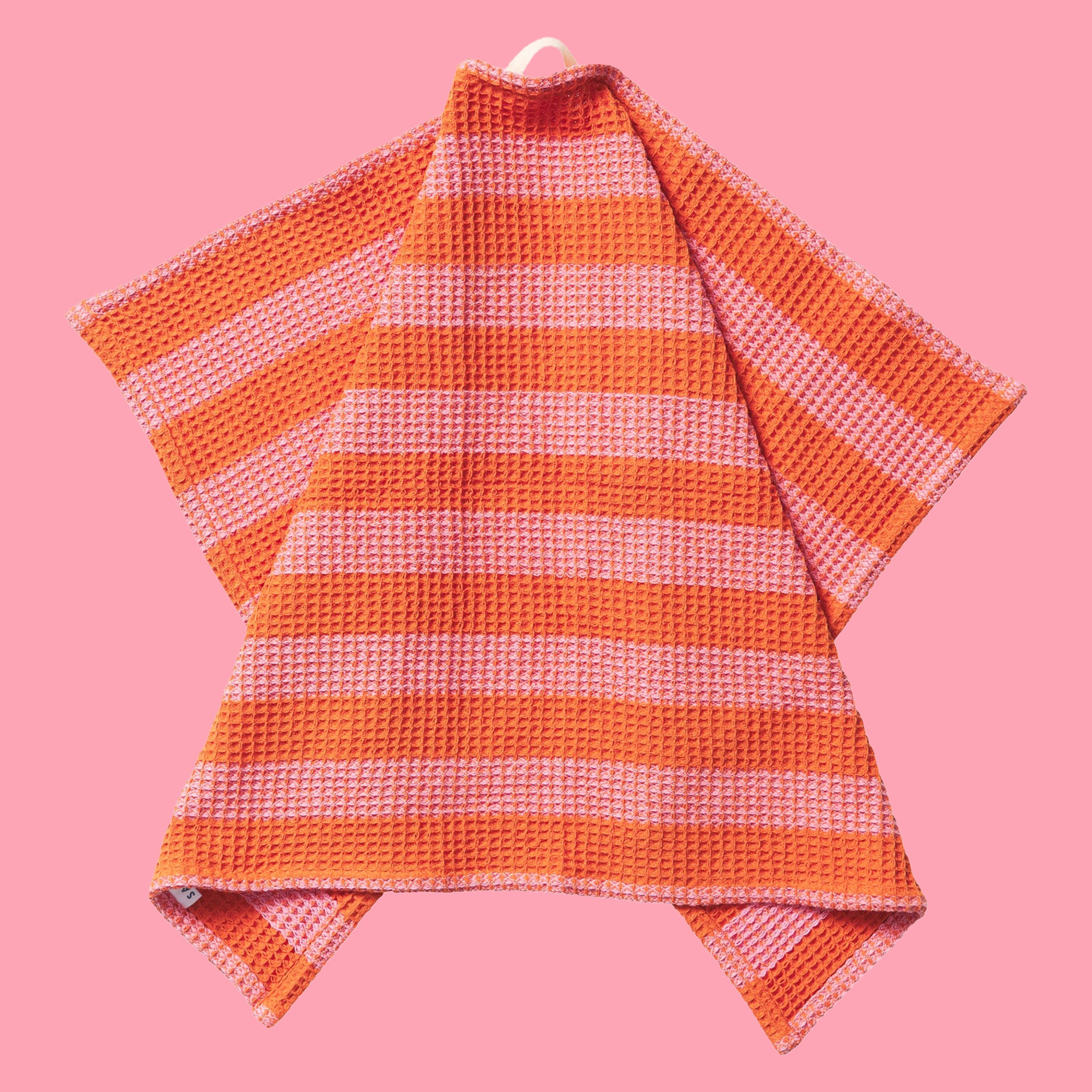 A pink and orange striped waffle knit tea towel with a convenient loop for hanging. 