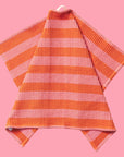 A pink and orange striped waffle knit tea towel with a convenient loop for hanging. 