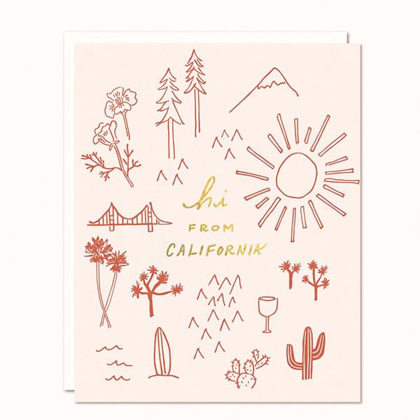 Photo of a cream colored greeting card on a white background that reads "hi from California" in gold leaf. Rust colored simple line drawings of poppy flowers, trees, mountains, a sun, cacti, waves and the Golden Gate Bridge surround the writing. White envelope is included. 