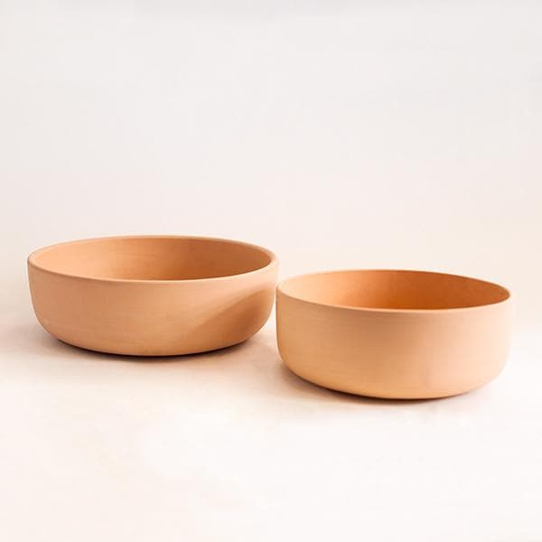 A terracotta ceramic bowl that has a low profile and a wide opening. There are two sizes available and photographed here.
