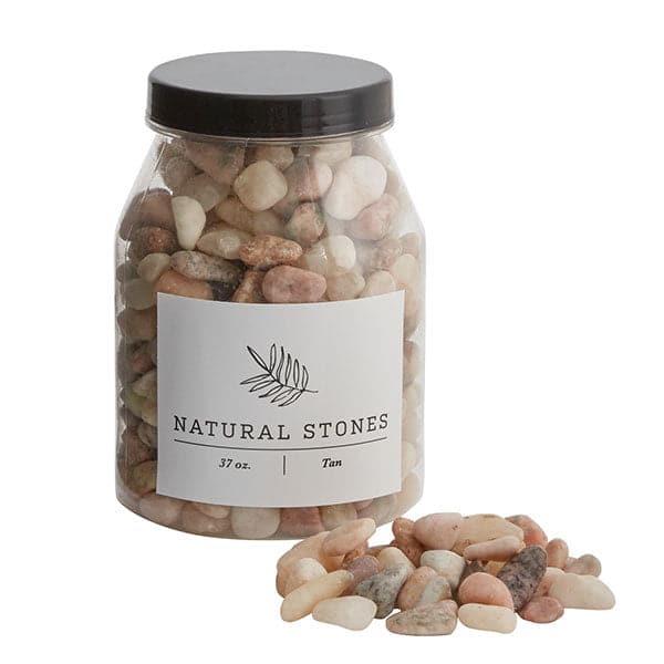 On a cream background is an assortment of natural tan and cream colored stones in a plastic jar with a black lid. 