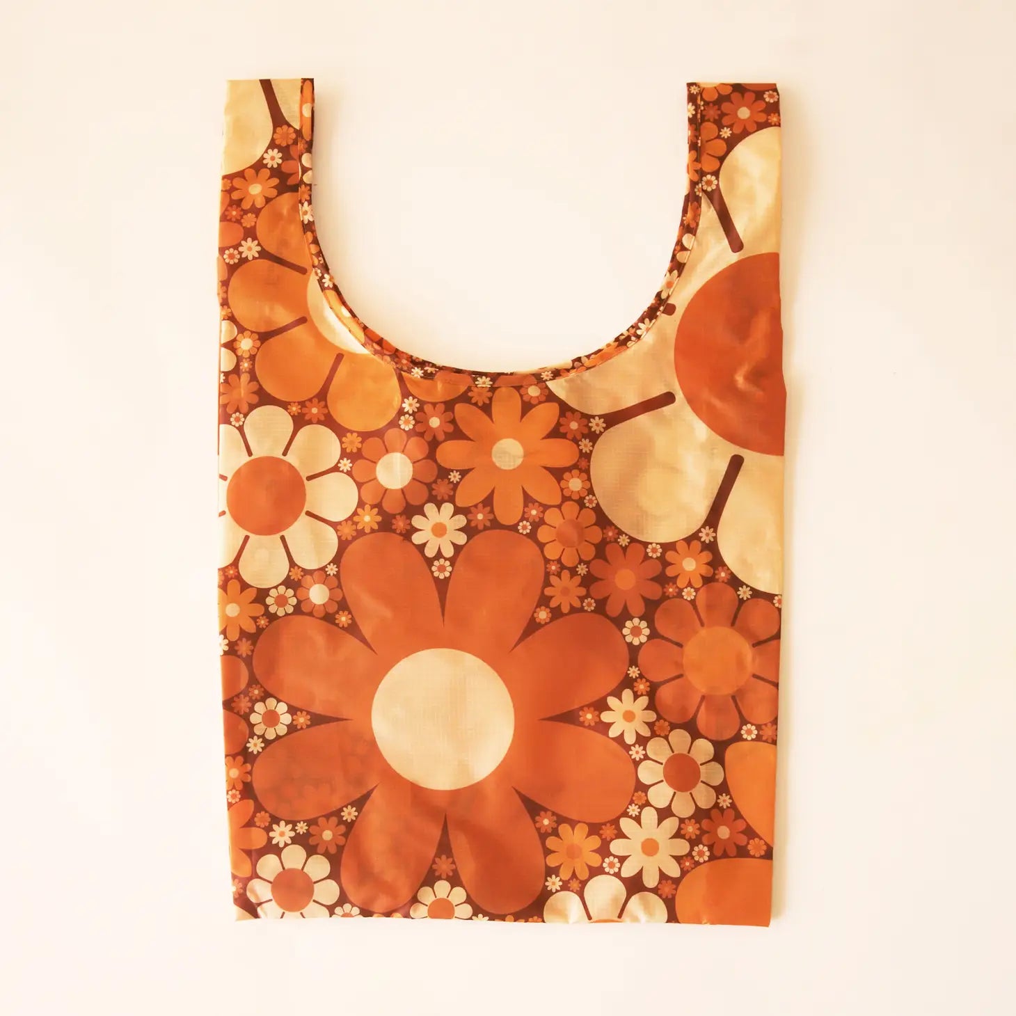 An orange reusable nylon tote bag with a swoop opening and a variety of different sized daisies all ranging in tones of warm creams, light yellow and oranges.