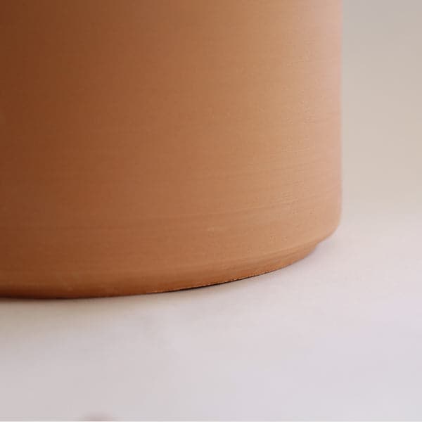On a white background is a terracotta cylinder planter with a raw terracotta finish.