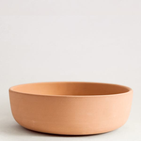 A terracotta ceramic bowl that has a low profile and a wide opening.