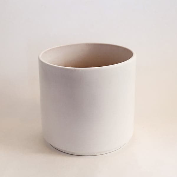 In front of a white bacground is the smallest of the three white cylinder ceramic planters. 