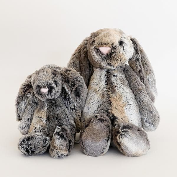 Two, one small and one large, stuffed animals in the shape of mottled grey and gold colored rabbits, with long floppy ears, arms and legs.