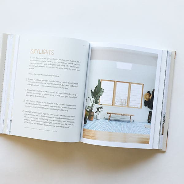 A book lays open on the table. Text fills the left page titles "Skylights", the right page shows a bright room with a large window.