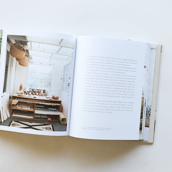 Books lays open on a table. The left page shows a picture of a indoor porch workshop, the left page is filled with text.