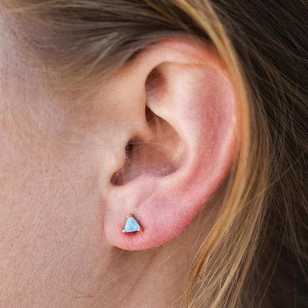 A set of triangular shaped blue opal stud earring with gold accents, post and backing.