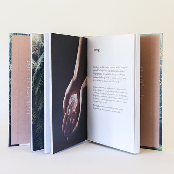 A photograph of the inside of the book that features topics like &quot;Energy&quot; and more text below it as well as beautiful images. Pictured here is hands holding a crystal.