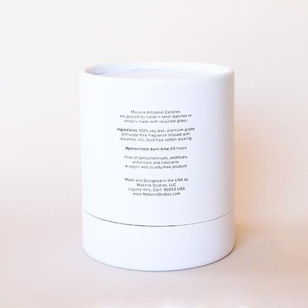 On a cream background is a white cardboard candle container with a clear glass jar candle inside with a single wick candle inside along with black text on the front that reads, "Neroli Blossom".