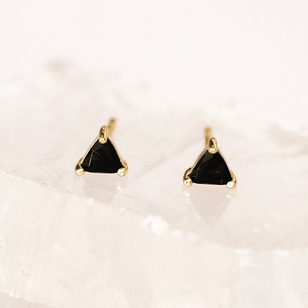 A triangle stud earring made of black tourmaline and 18k gold plated details and post.