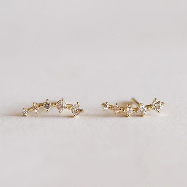 A gold crawler stud earrings with five champagne cubic zirconia stones gradually increasing in size toward the end of the earring.