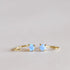 In front of a white background is a pair of gold huggies with a round green opal on the top. 