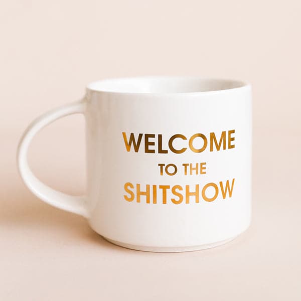 Classic white ceramic mug with a thin round handle labeled &#39;Welcome to the Shitshow&#39; in reflective gold lettering. 