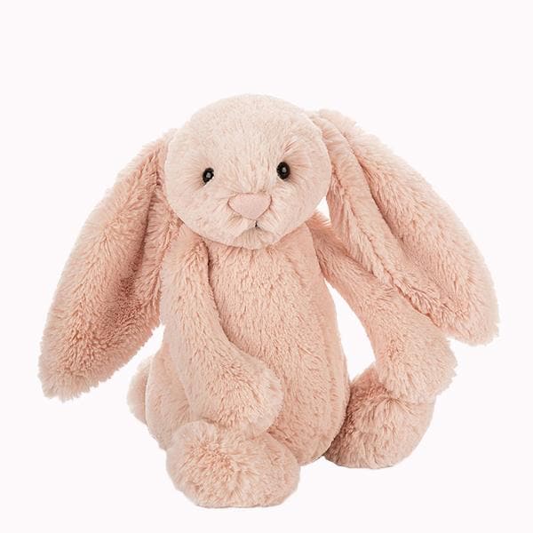 Soft stuffed animal in the shape of a pink blush colored rabbit with long floppy ears, arms and legs.