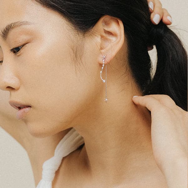 A dainty dangly earring with a star stud and a chain hanging down the back side and a wavy cubic zirconia studded down the front.