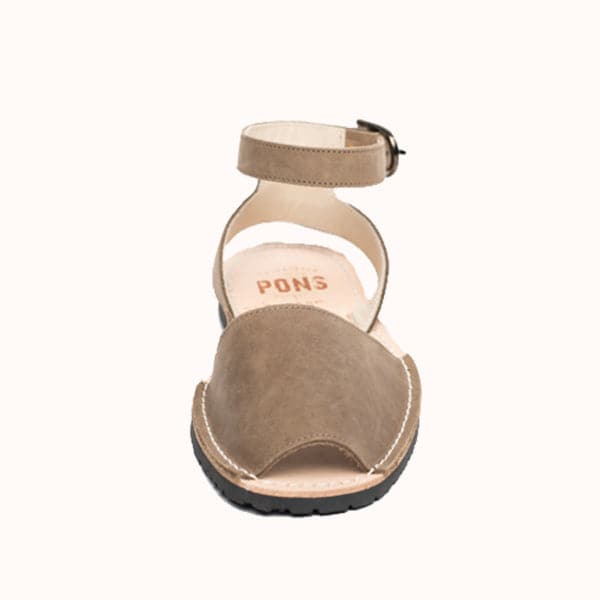 Single Avarca sandal made of lightweight rubber molded to a light natural leather sole. White stitching lines the front strap to the sole of the shoe. The sandal's front strap is taupe toned and large enough to cover the front half of foot. Above is a thin leather ankle strap with a buckle closure.