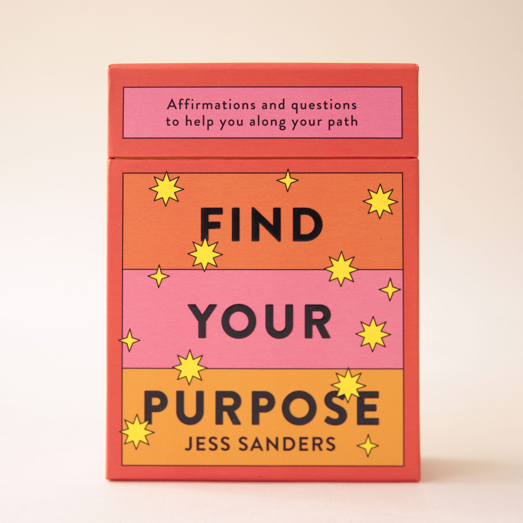 An orange, yellow and pink deck of cards with the words, "Find Your Purpose" on the front as well as "Affirmations and questions to help you along your path" in black writing.