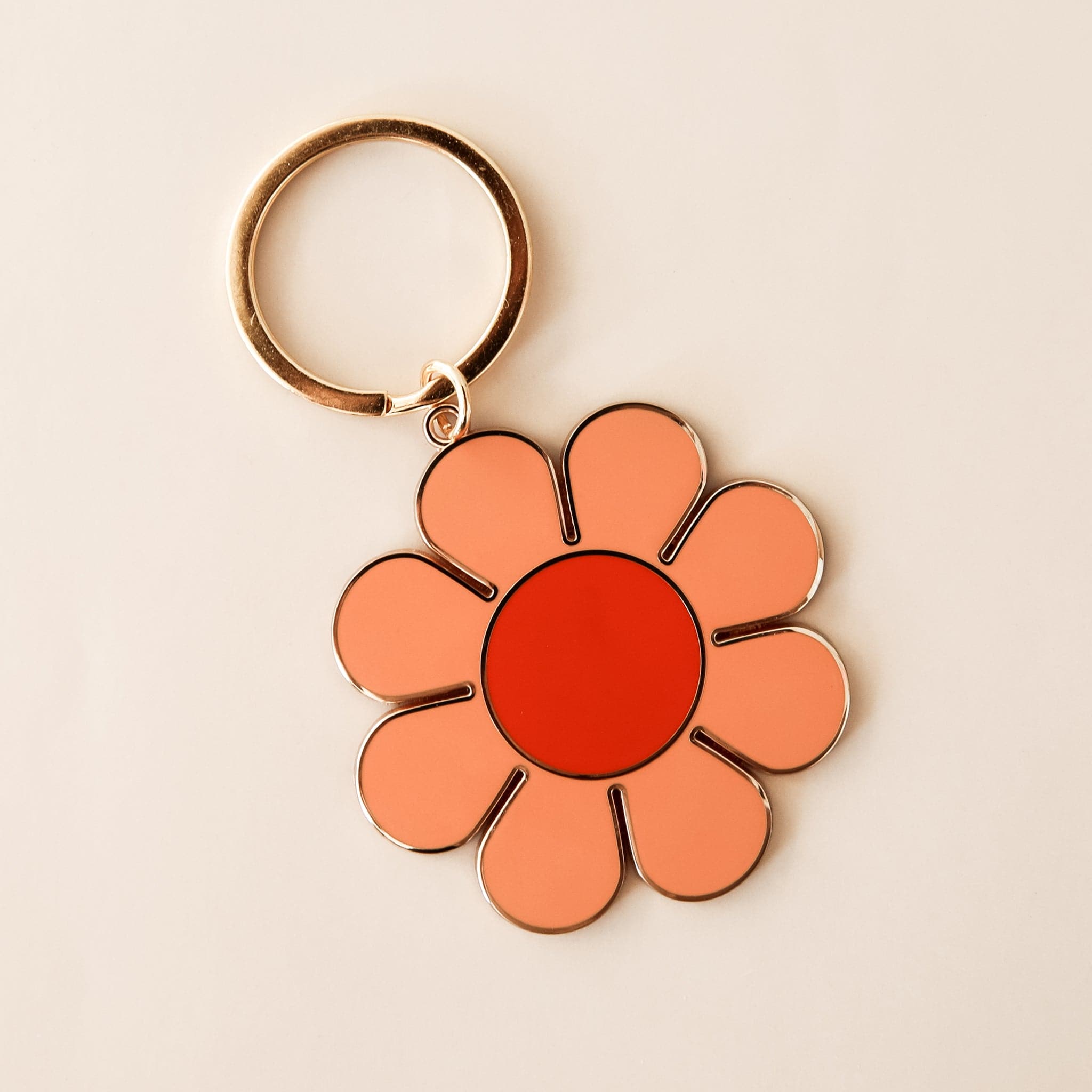 Light orange daisy keychain on a gold ring with a red center. 
