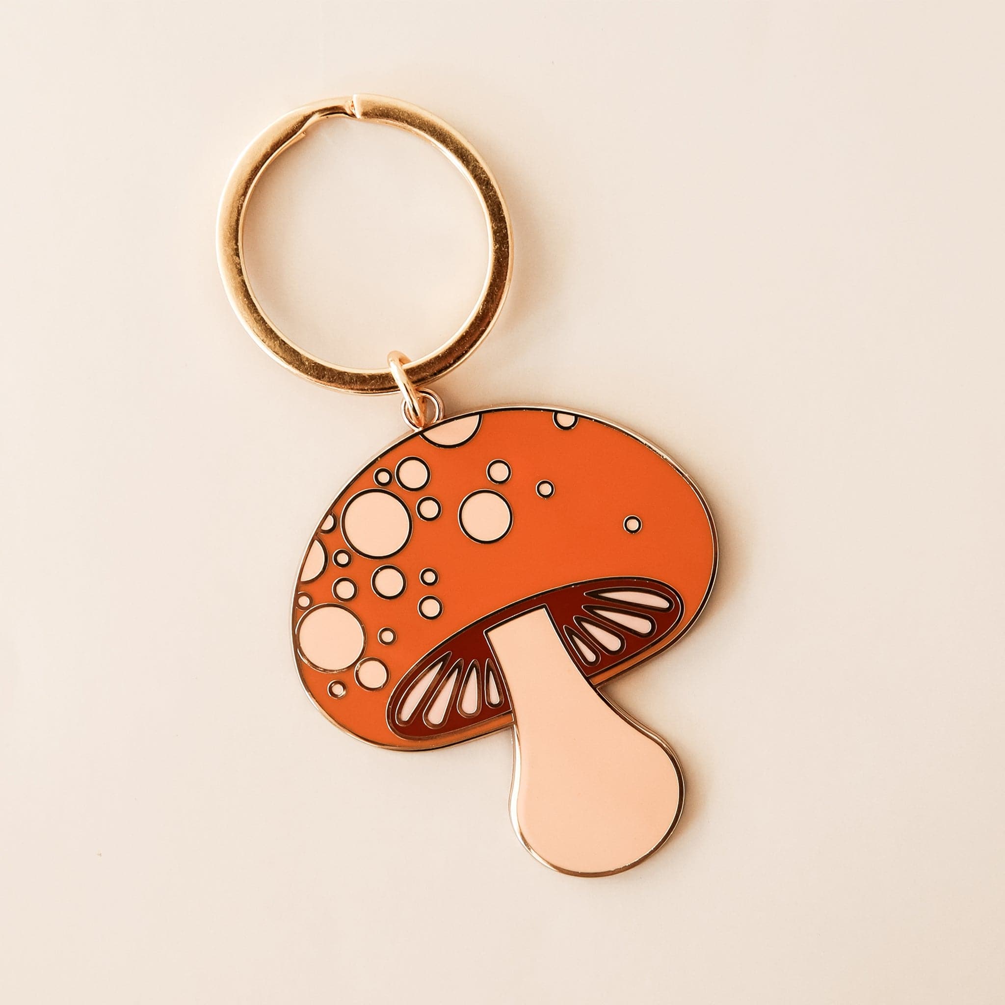 Mushroom keychain with red top with soft pink spots. The keychain is complete with gold detailing and a golden key ring. 