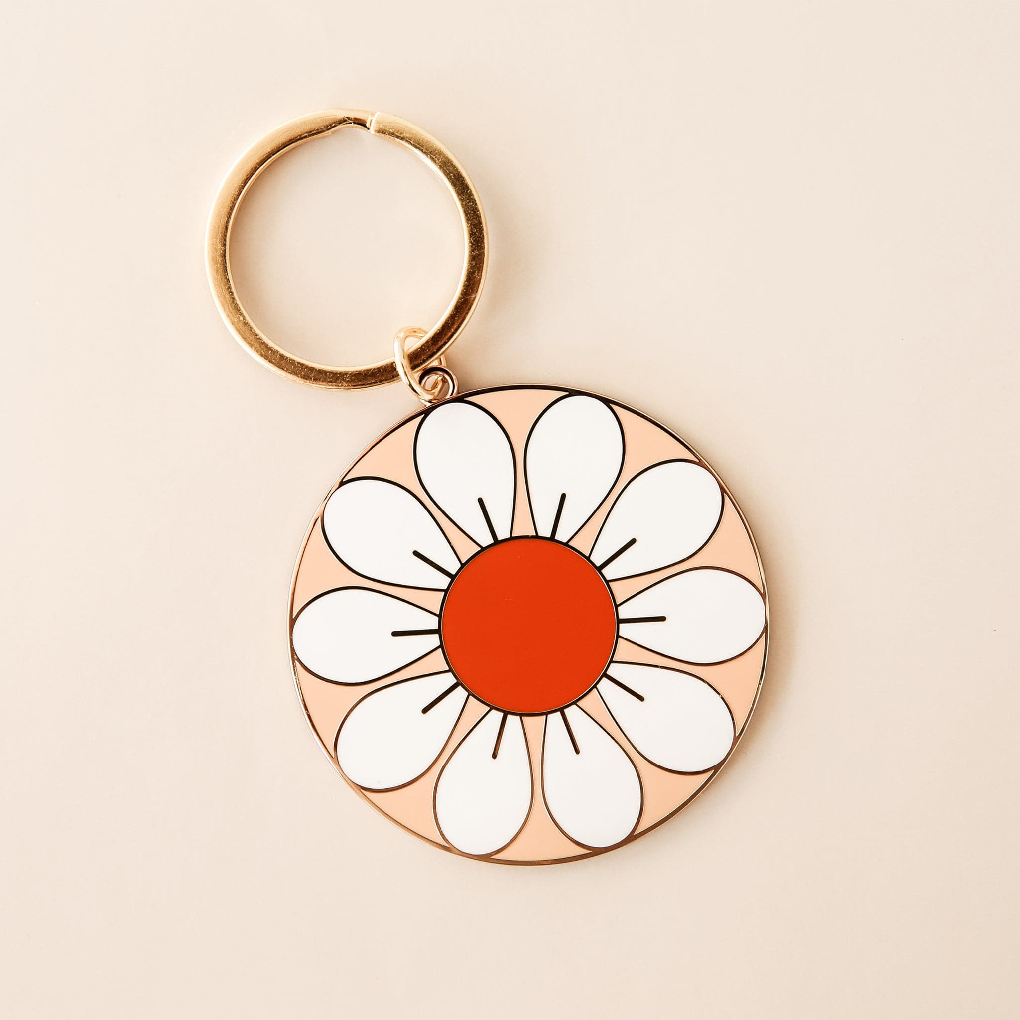 Circle flower keychain with white petals and red-orange center. The keychain is complete with a golden key chain ring. 