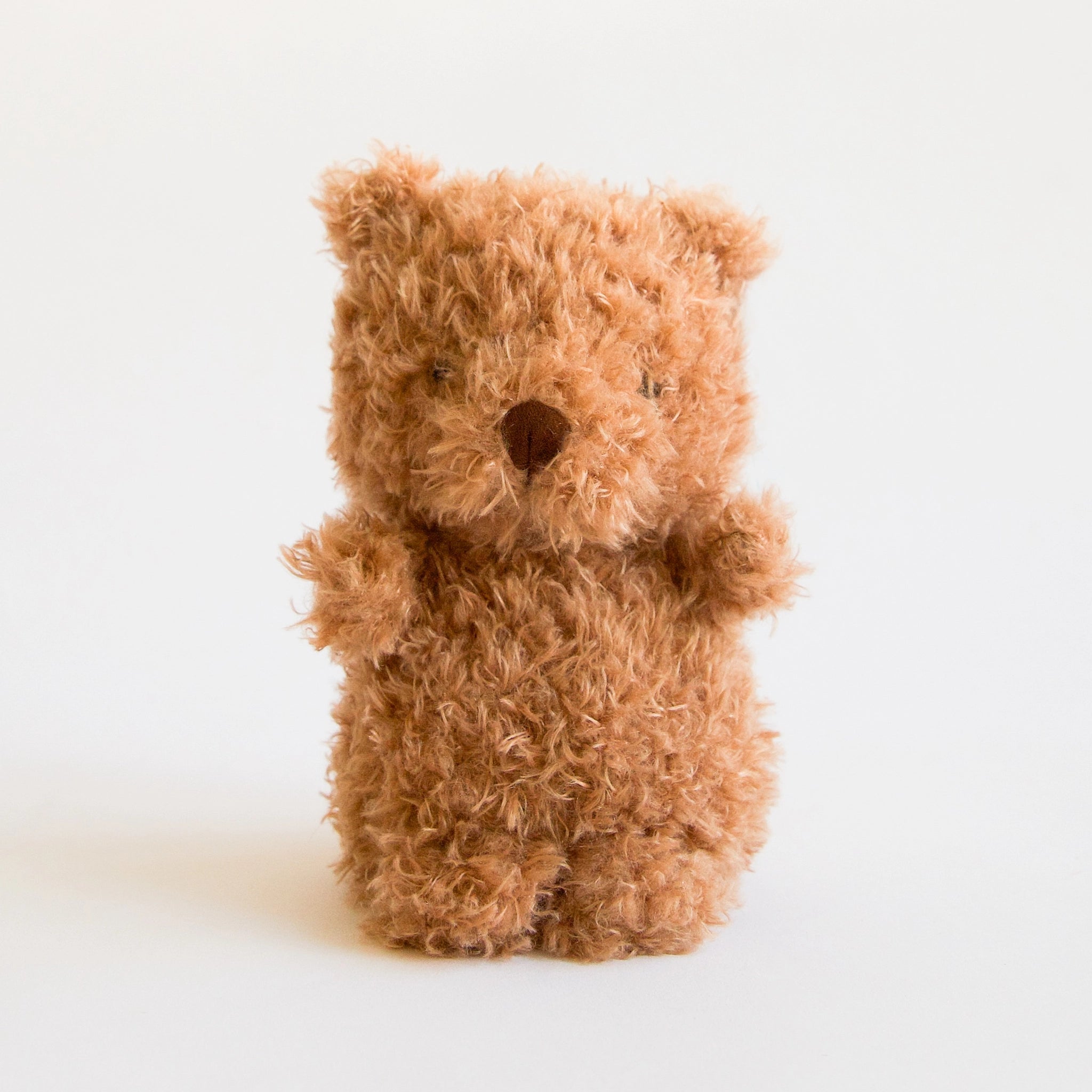 A small cuddly bear stuffed animal with chestnut brown fur, a brown nose and small little ears.