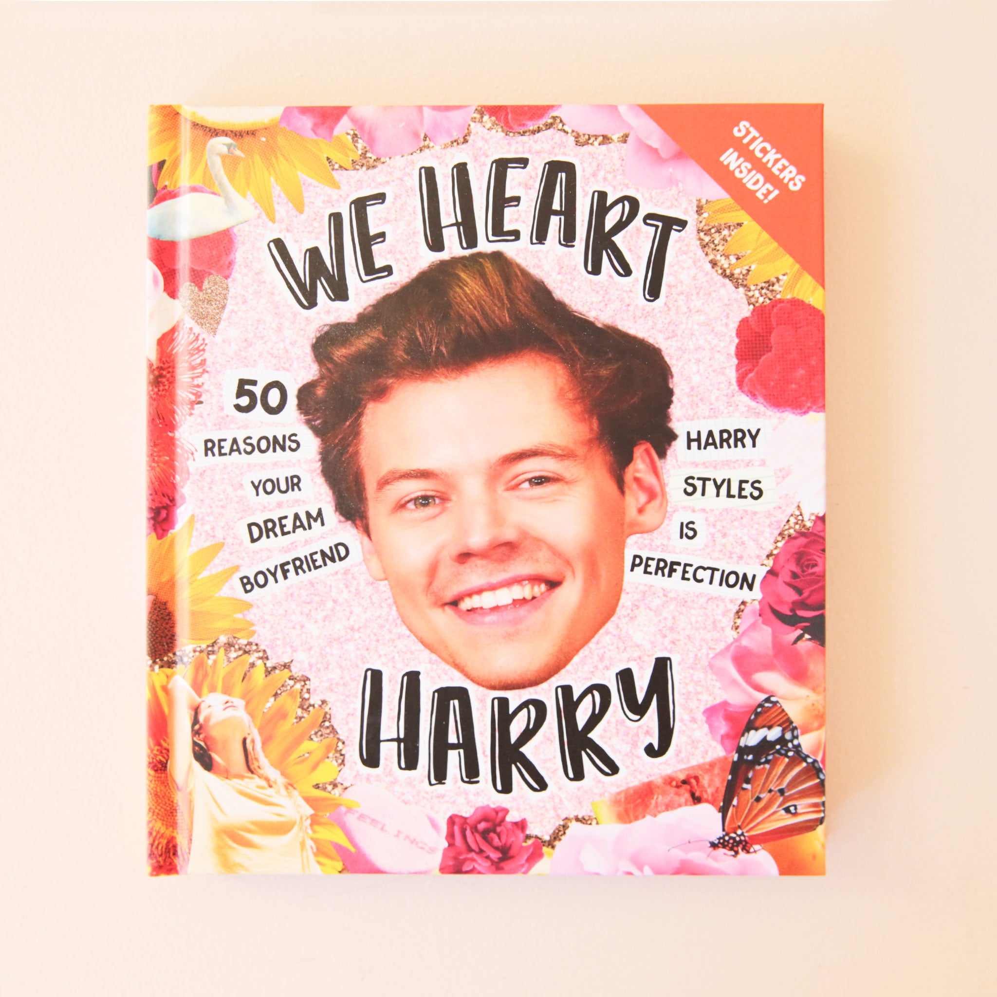 A vibrant pink and yellow book cover with a photo of Harry Styles face front and center as well as text that reads, &quot;We Heart Harry&quot;, &quot;50 Reasons Your Dream Boyfriend Harry Styles Is Perfection&quot;.