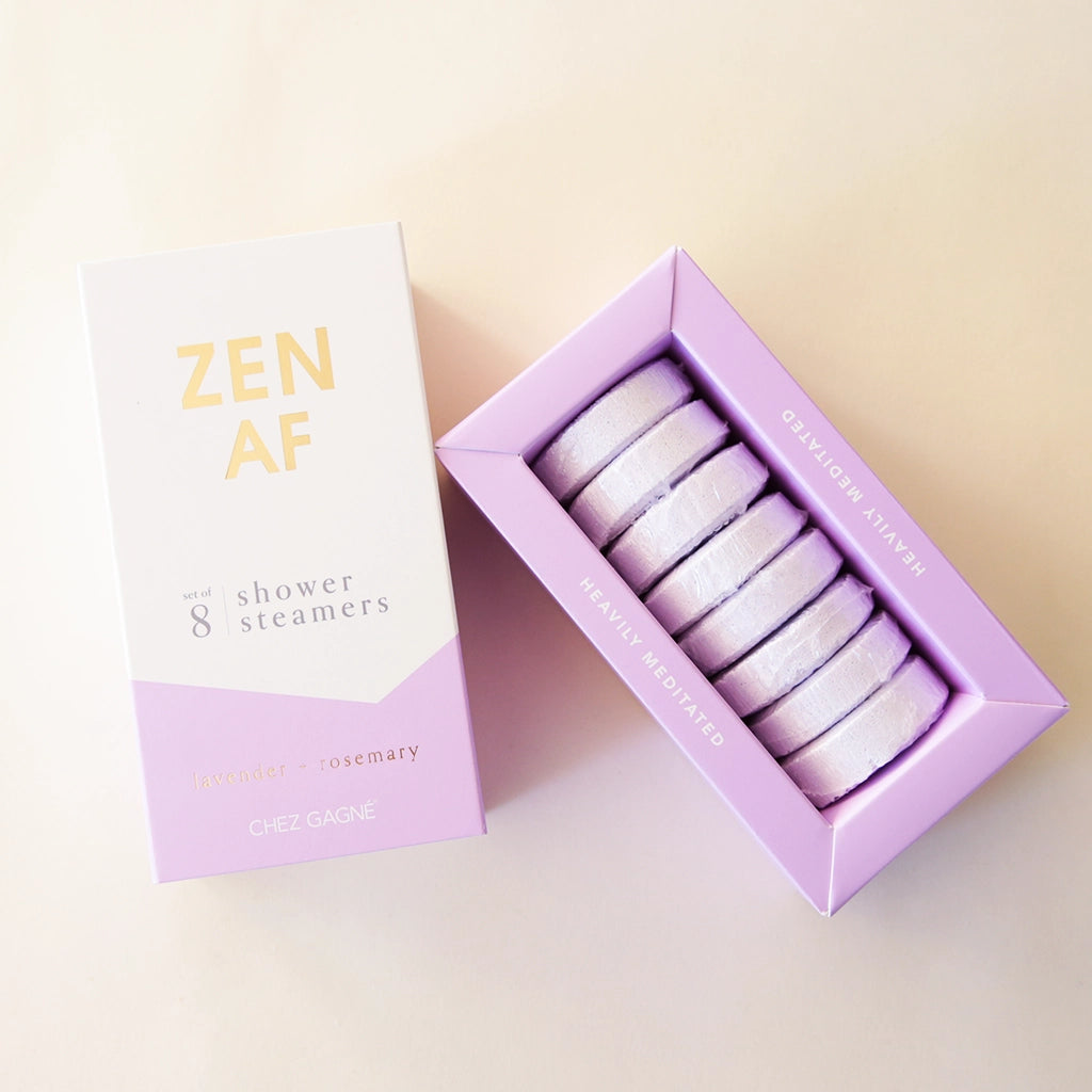 Eight lilac purple shower steamer tablets inside of a purple and white box that reads, "Zen AF" in gold text across the front.