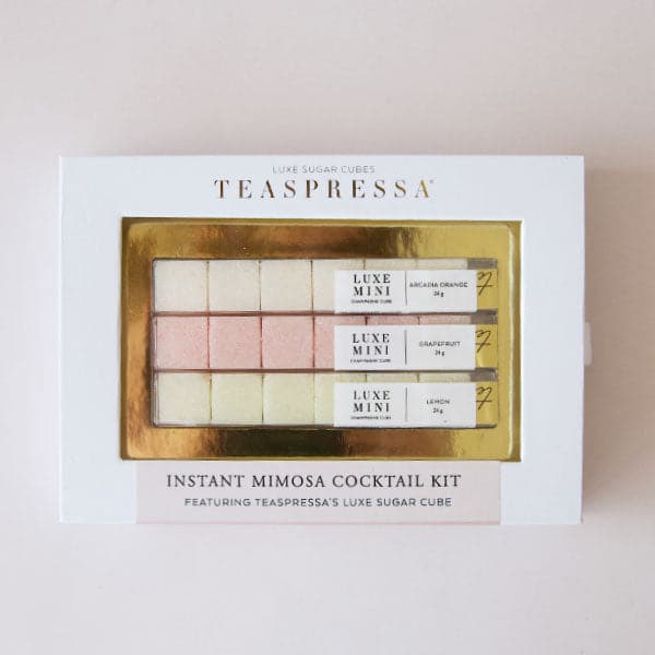 On a cream background is a set of three different flavored sugar cubes made for instant mimosa cocktails. The packaging reads, "Teaspressa Instant Mimosa Cocktail Kit".