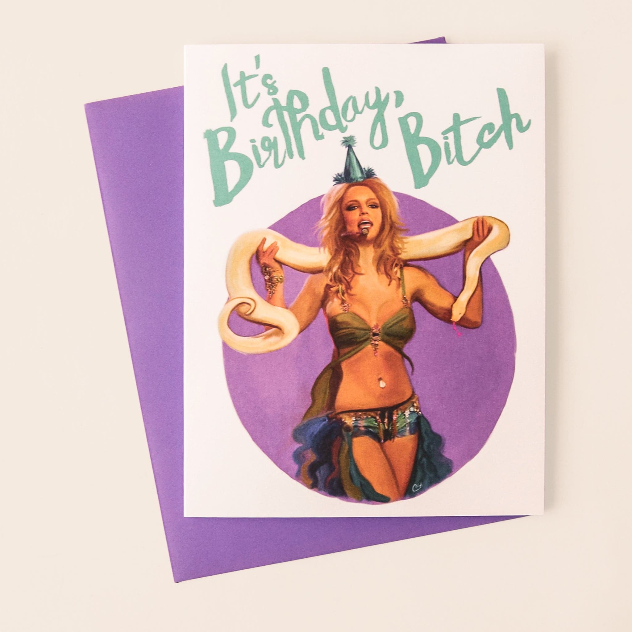 White greeting card with illustration of Britney Spears performing with boa snake and wearing party hat, with text &quot;It&#39;s Birthday, Bitch&quot; in teal text, with purple envelope. 