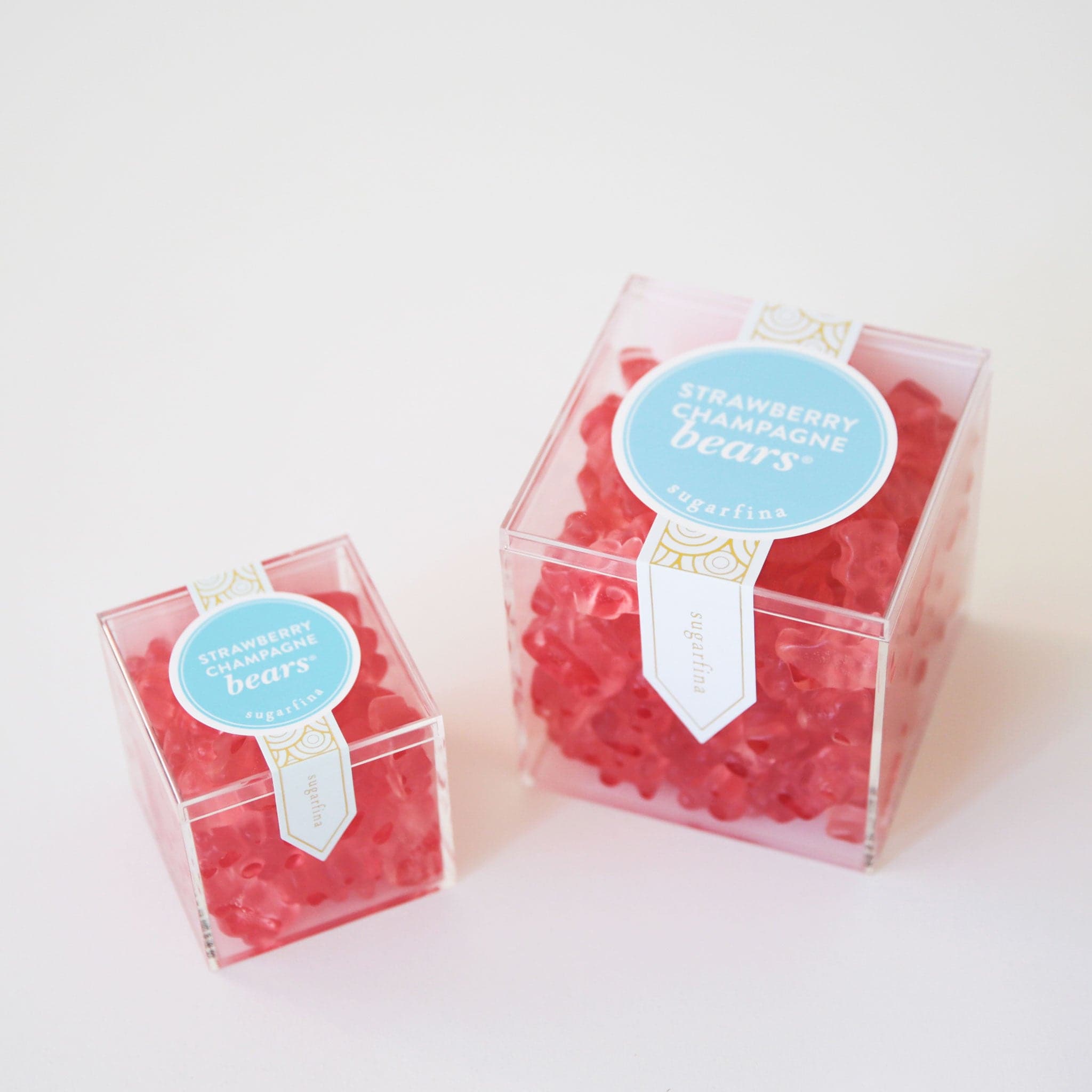 Two sizes of strawberry champagne gummy bears packaged in an acrylic box.