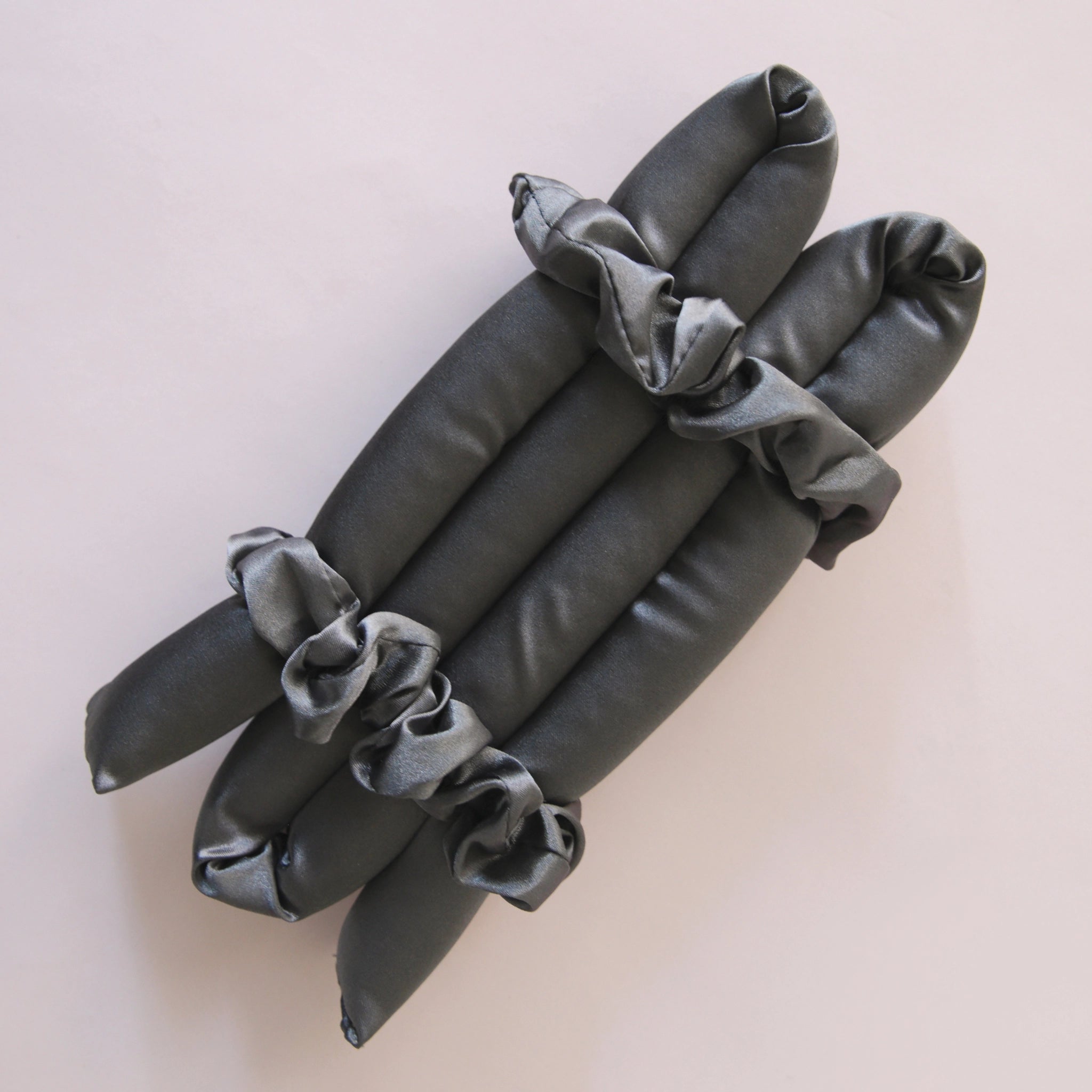 A black satin heatless curler with two included scrunchies.