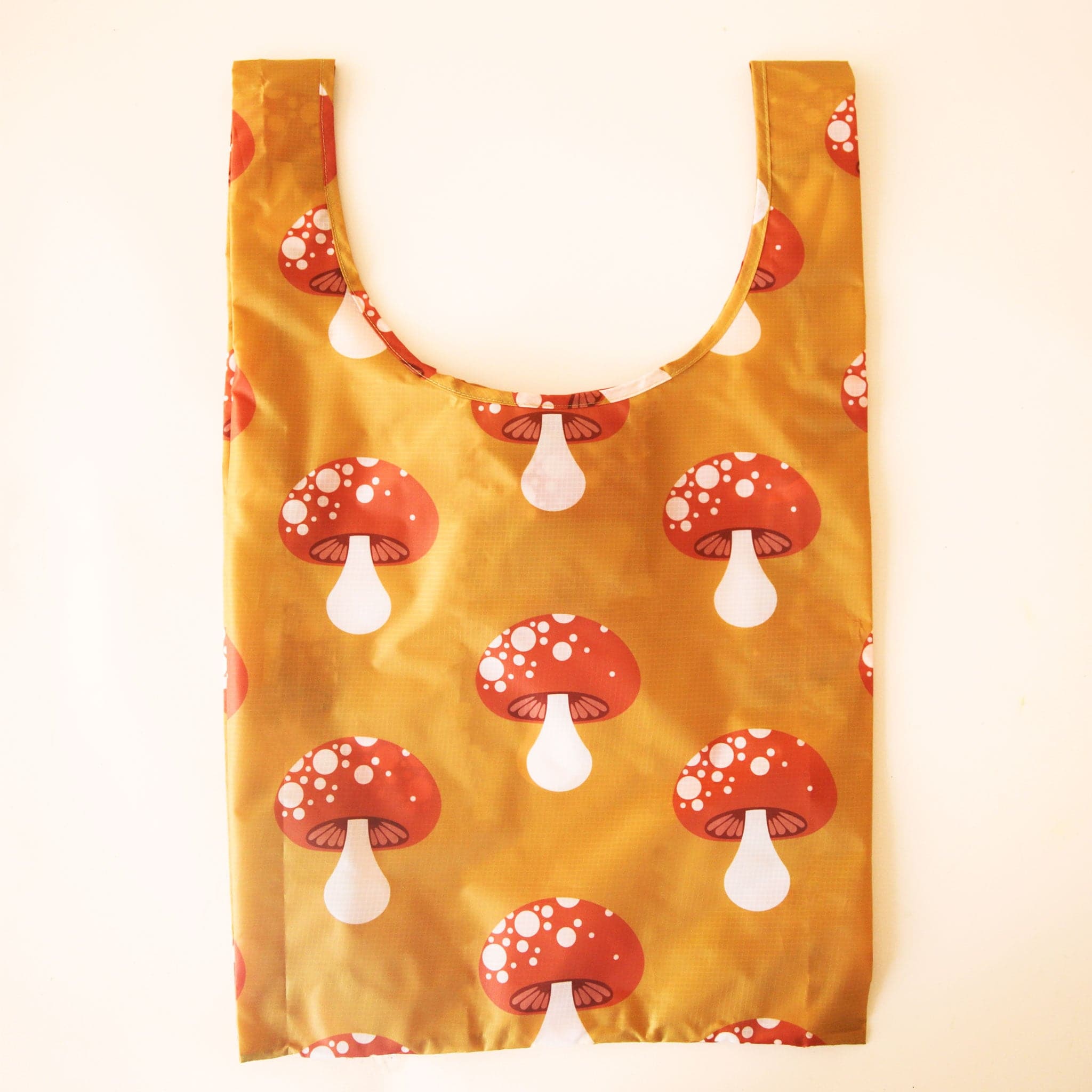 A mustard yellow nylon bag with reddish and cream mushroom print.
