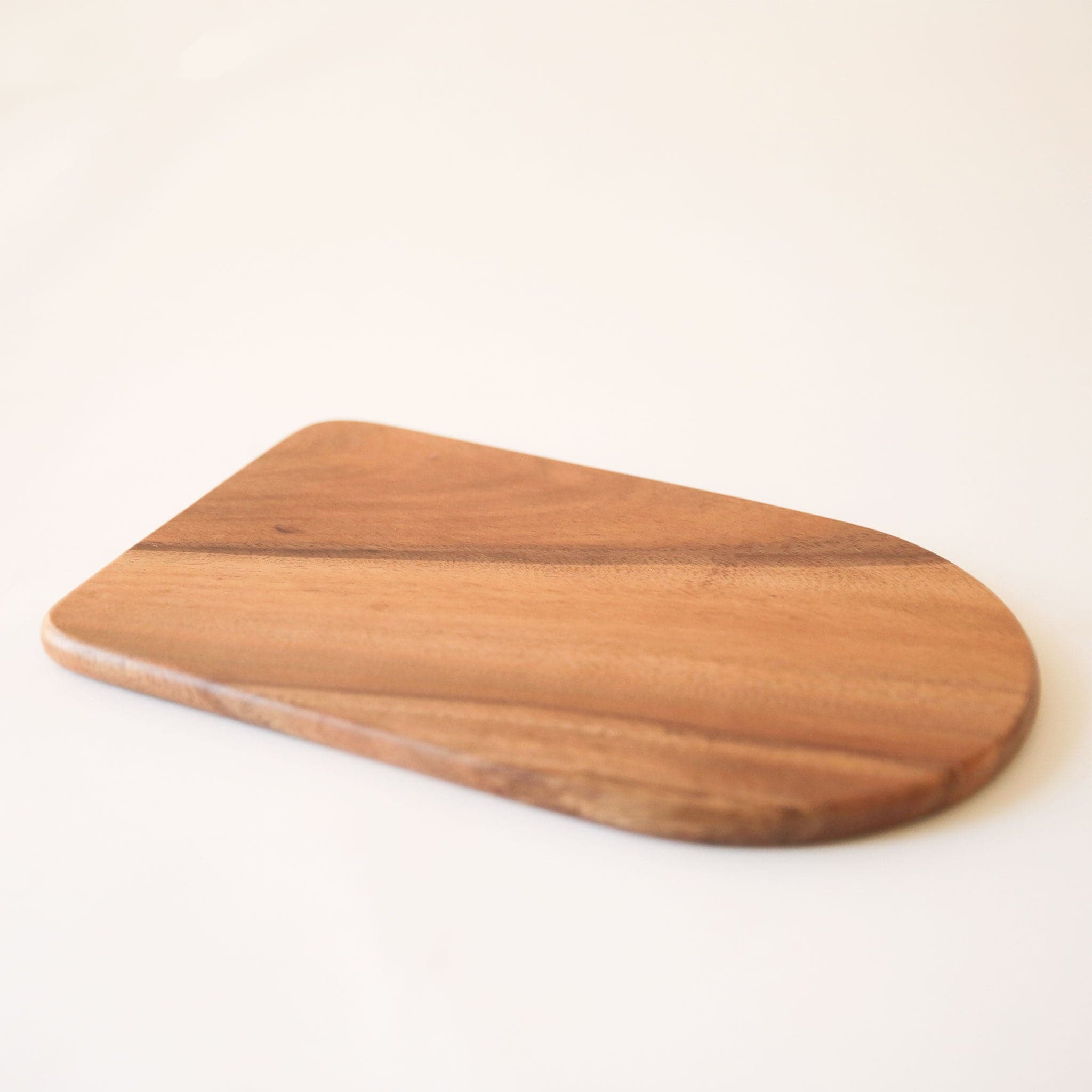 A wood cutting board with an arch on one side.
