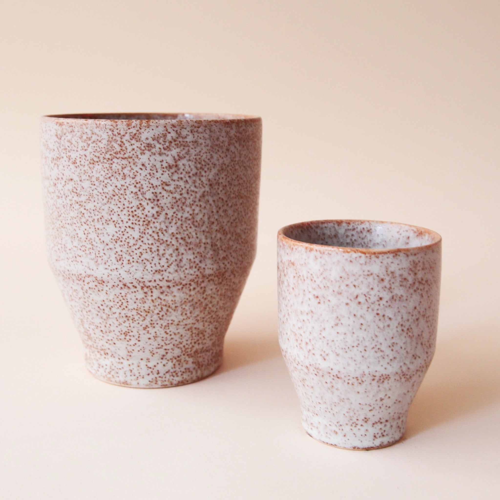 A small and large classic ceramic planter with a speckled white and tan texture.