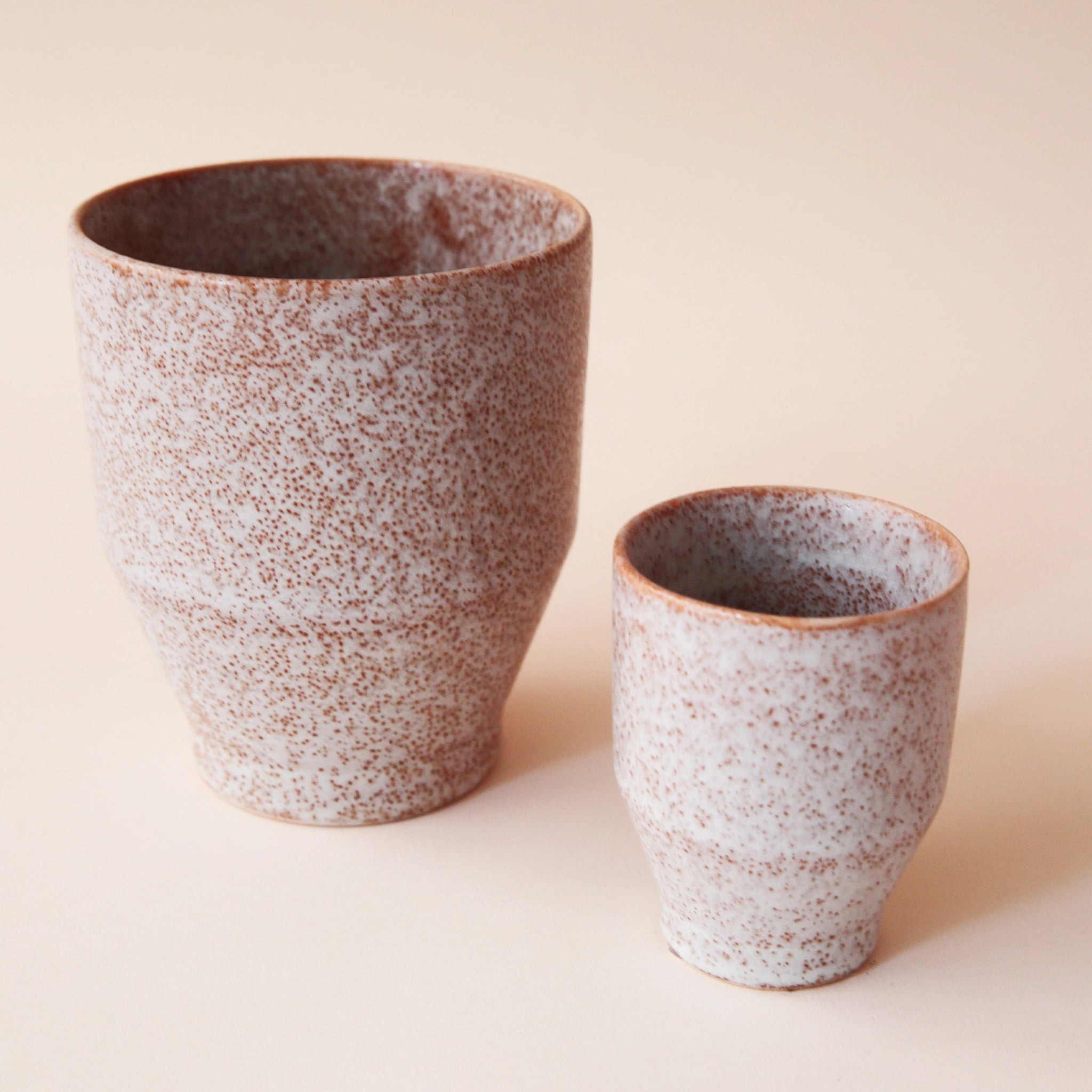 A small and large classic ceramic planter with a speckled white and tan texture.