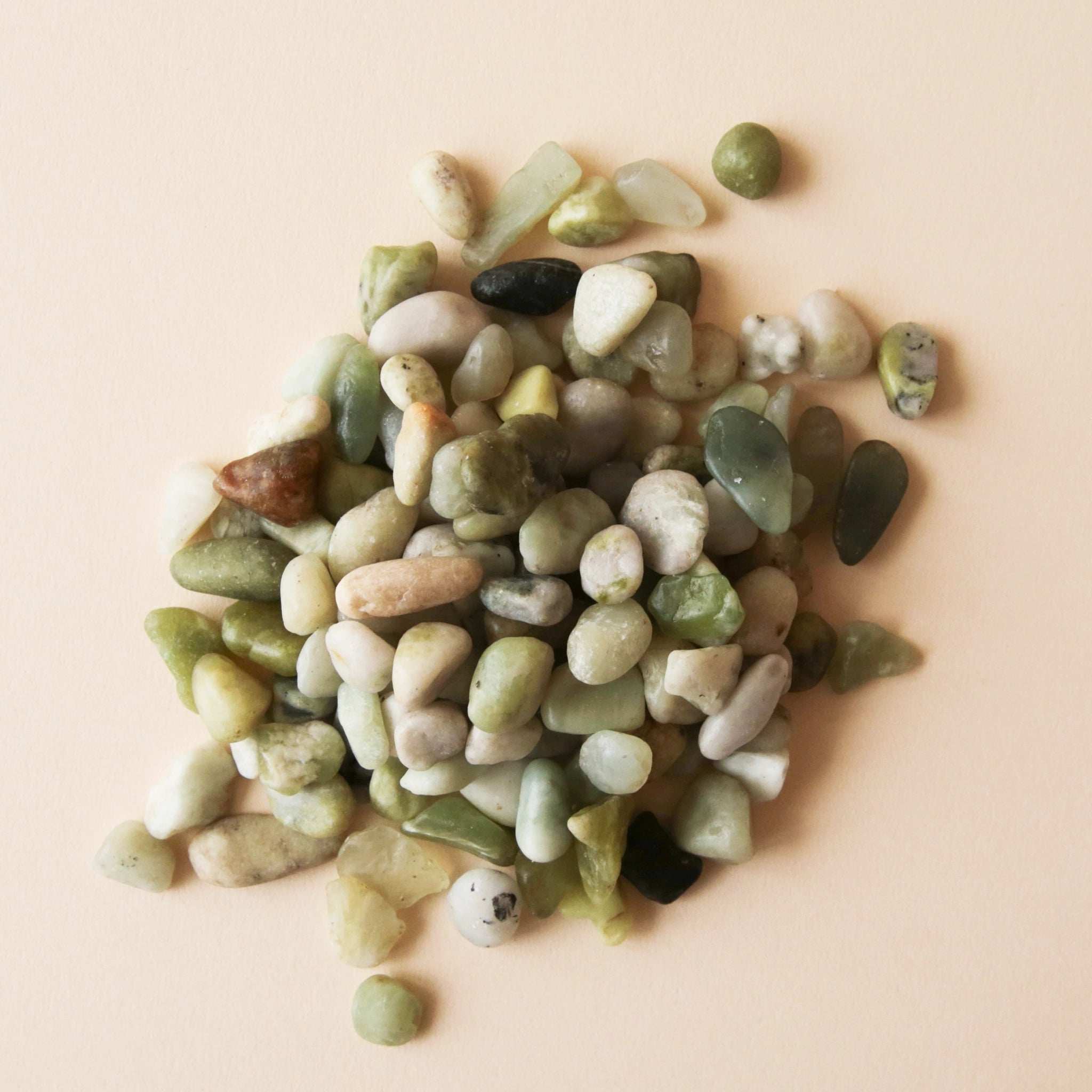 On a cream background is an assortment of light green and cream natural shaped stones. 