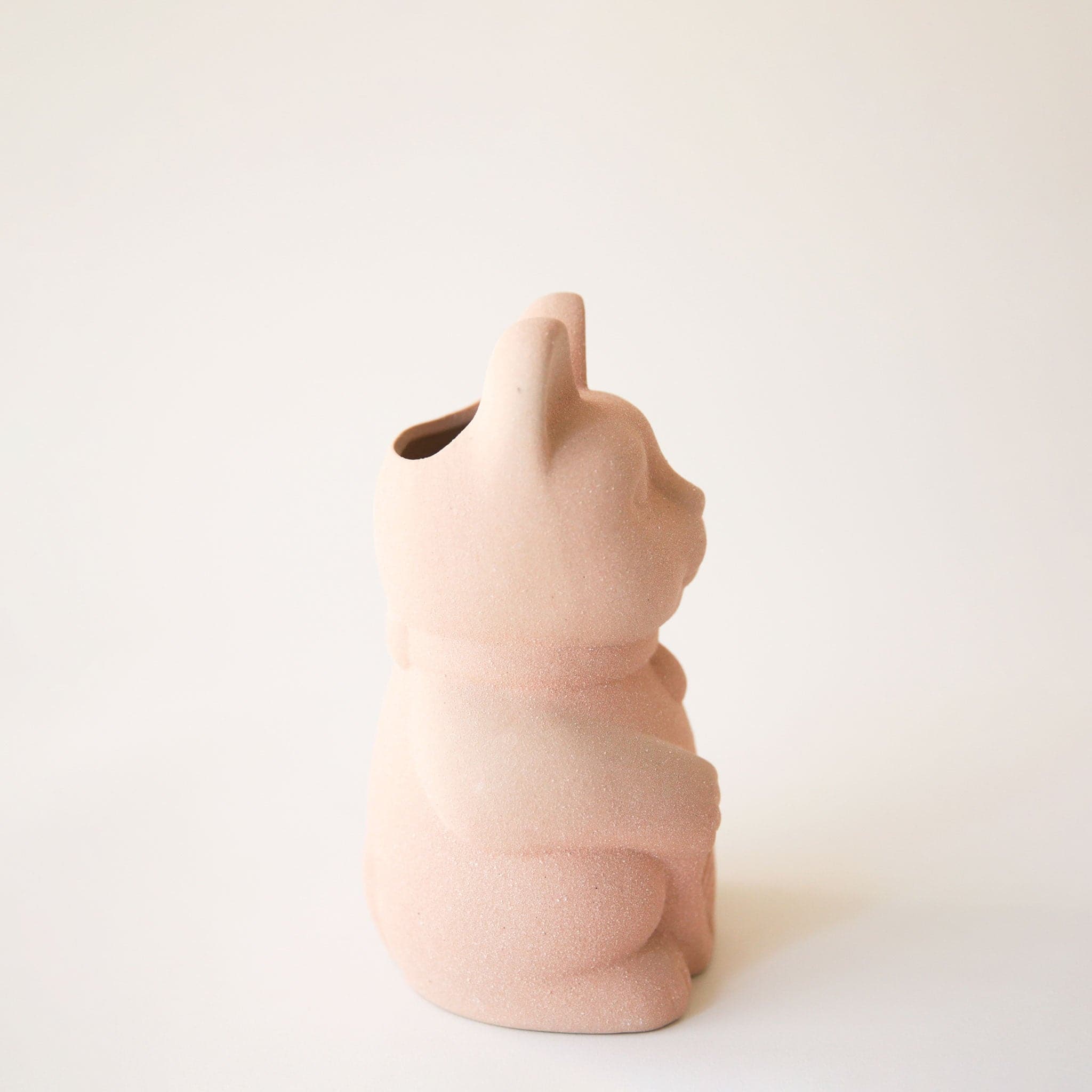 A ceramic lucky cat vase with its paw up in the waving position in a light blush shade.