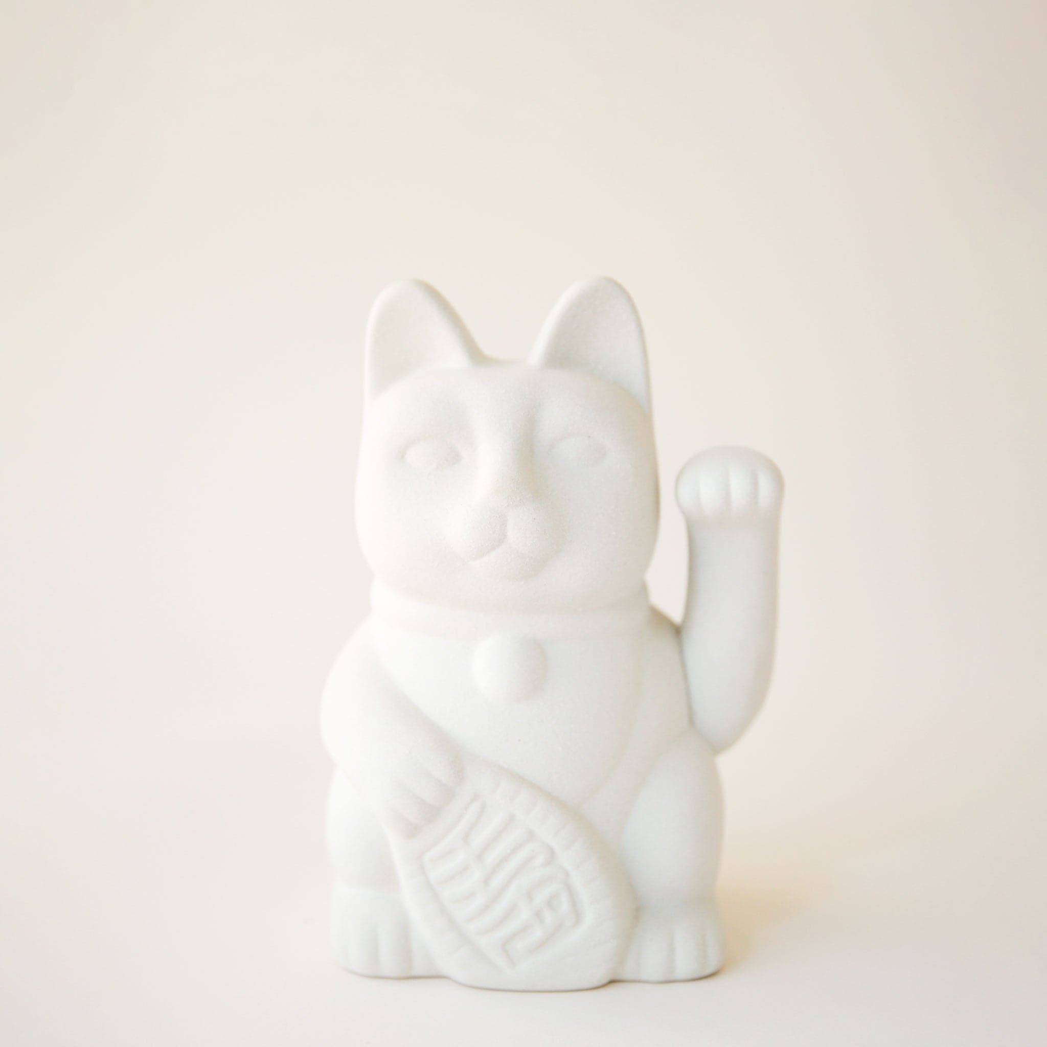 A ceramic lucky cat vase in white with its paw up in the waving position.