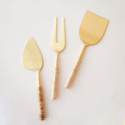 Thin gold cheese servers with a natural rattan wrapped handle. The set comes with a fork, knife and spatula.