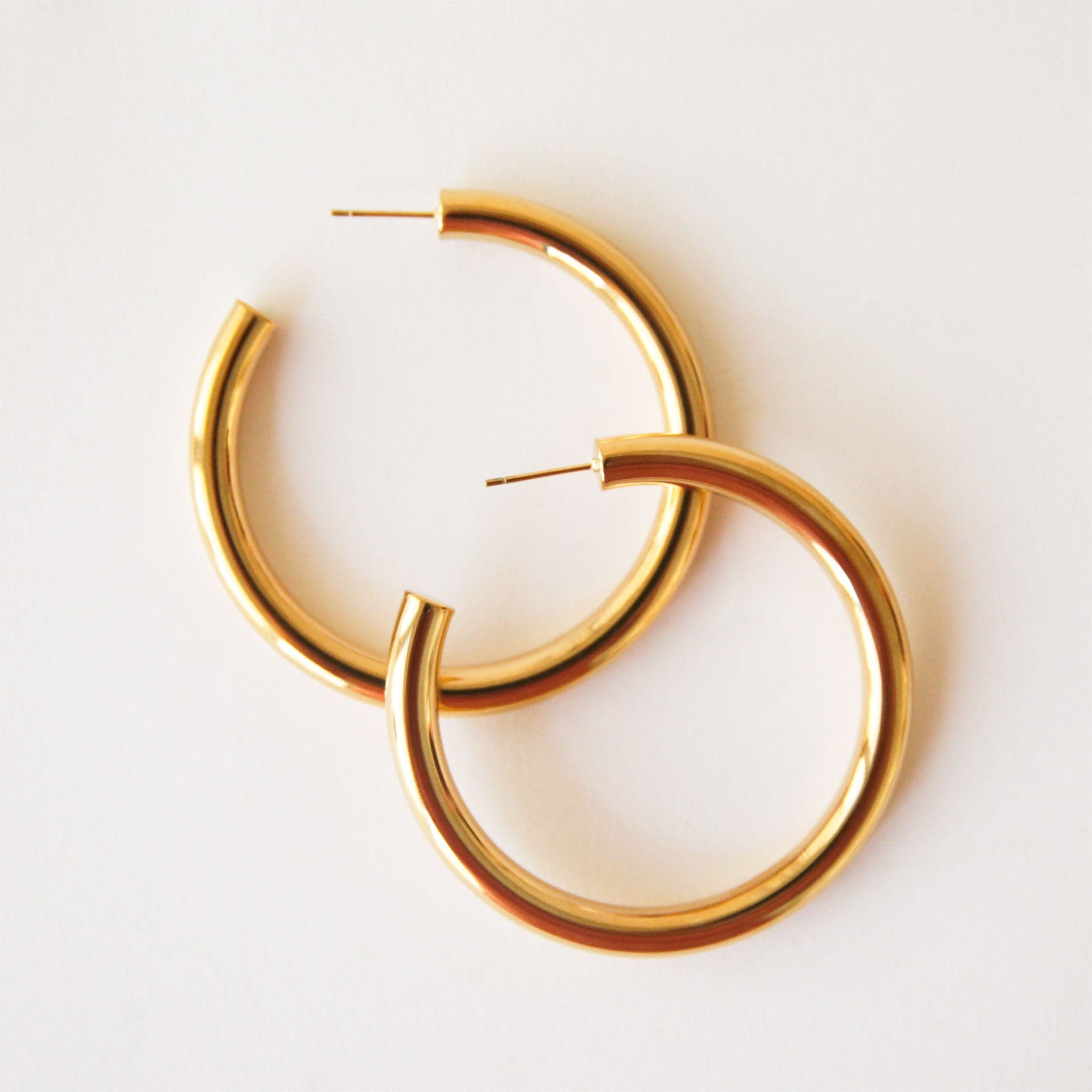 A chunky gold hoop earring with a straight backing and an open hoop.