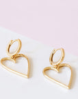 A pair of gold hoop earrings with a larger hold heart shape hoop attached to that.