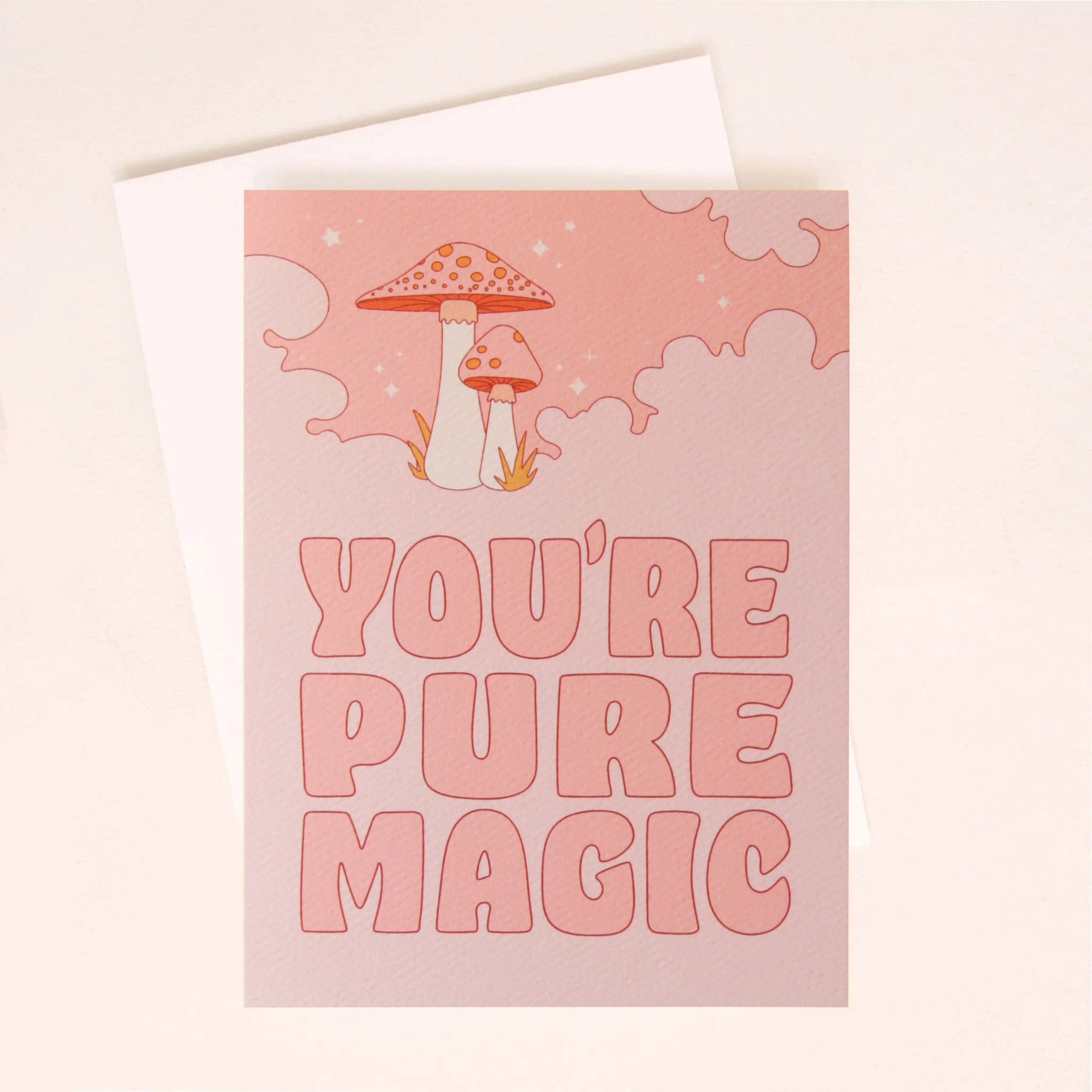 On a white background is a pink greeting card with a cloud and mushroom design and pink text that reads, "You're Pure Magic".