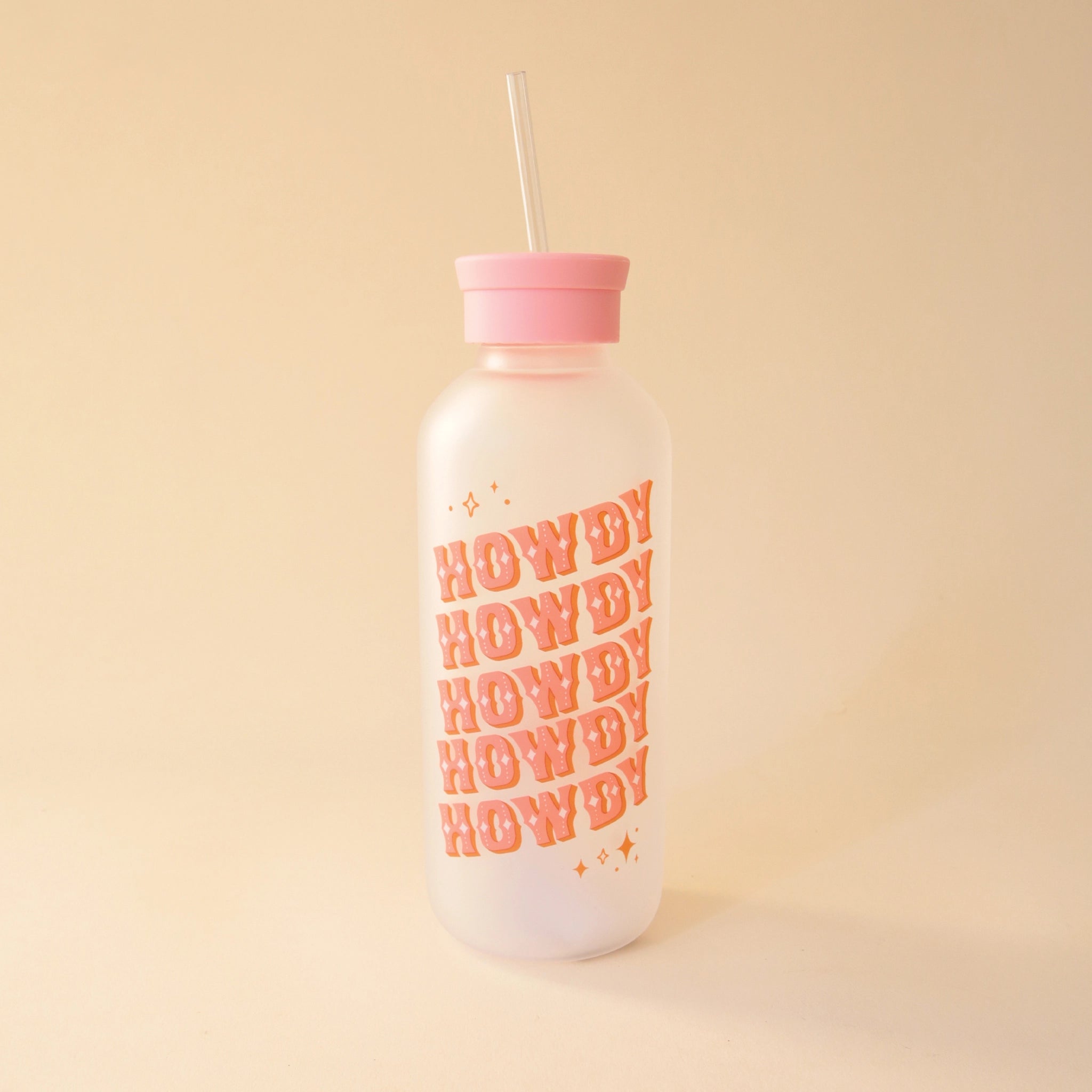 A glass water bottle with the word "HOWDY" in pink western style letters ,stacked five times at an angle on the front, a pink silicone lid with a straw coming out of the top.