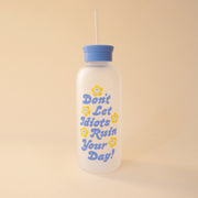 On a tan background is a clear water bottle with a blue lid and blue text that reads, "Don't Let Idiots Ruin Your Day" with smiley daisies all around it. 