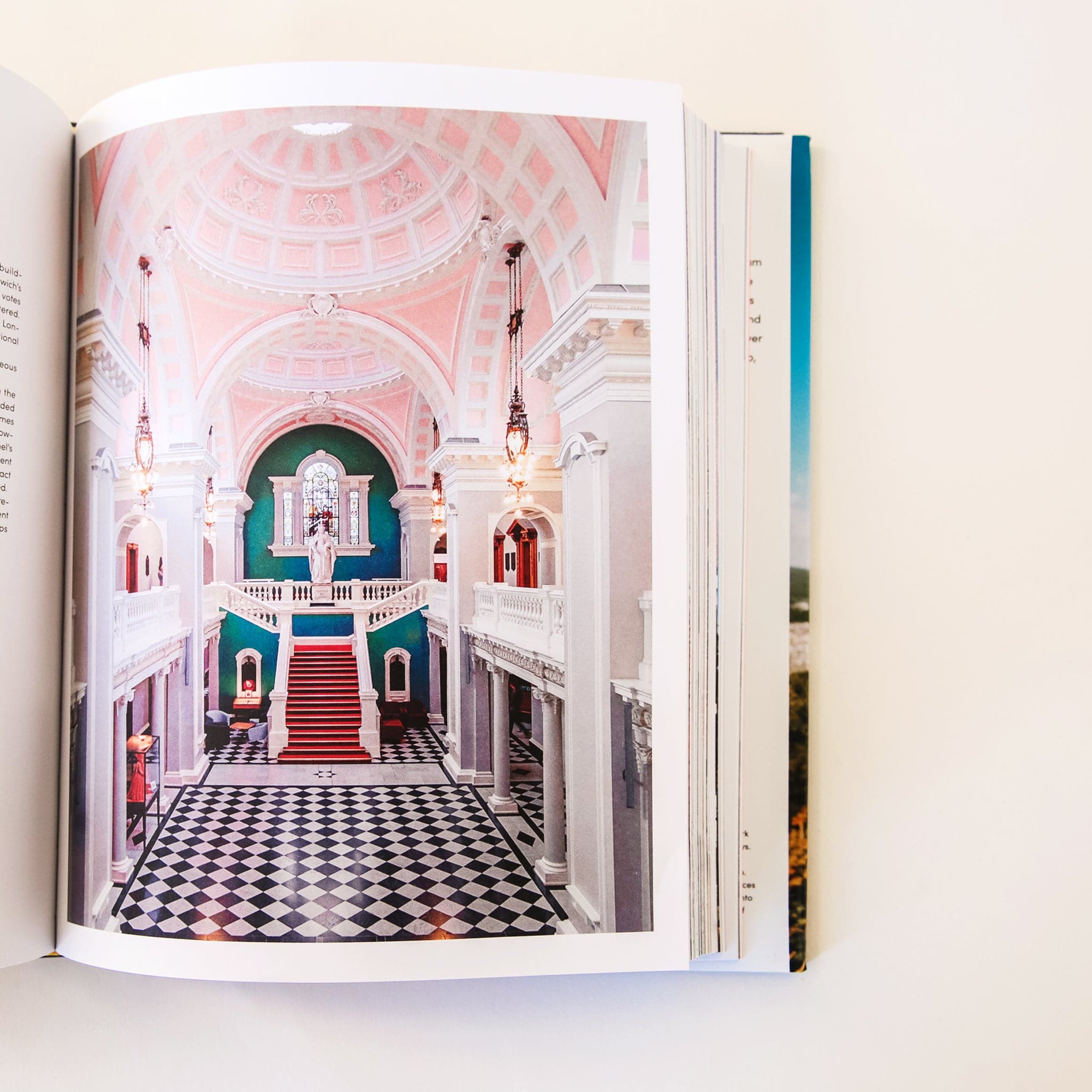 The Accidentally Wes Anderson book opened to a page featuring a large victorian style room with checker floors, high ceilings, and crown molding. 