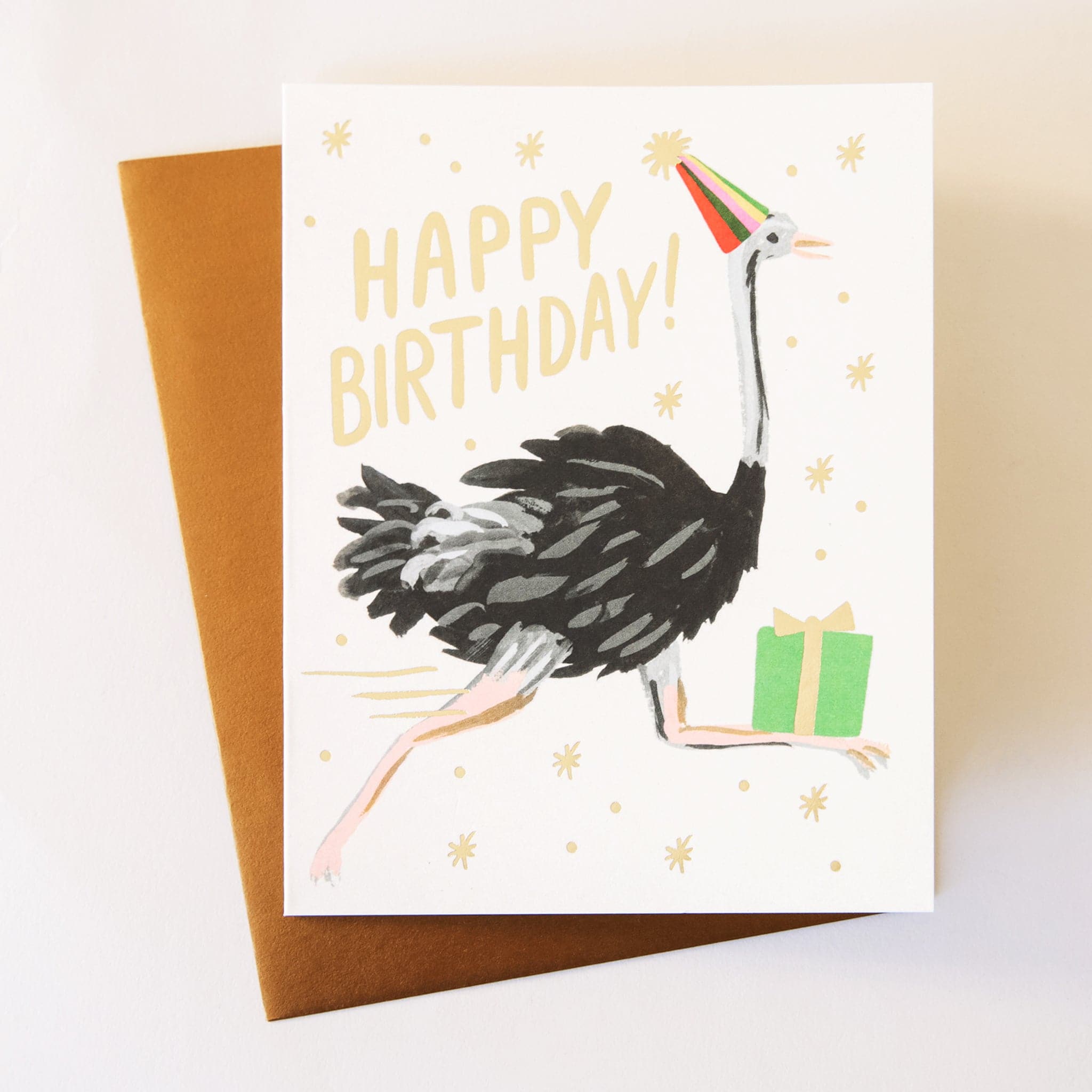 This adorable card has an ostrich running with a birthday present an a party hat. There is gold foil stars and lettering saying, "Happy Birthday!"