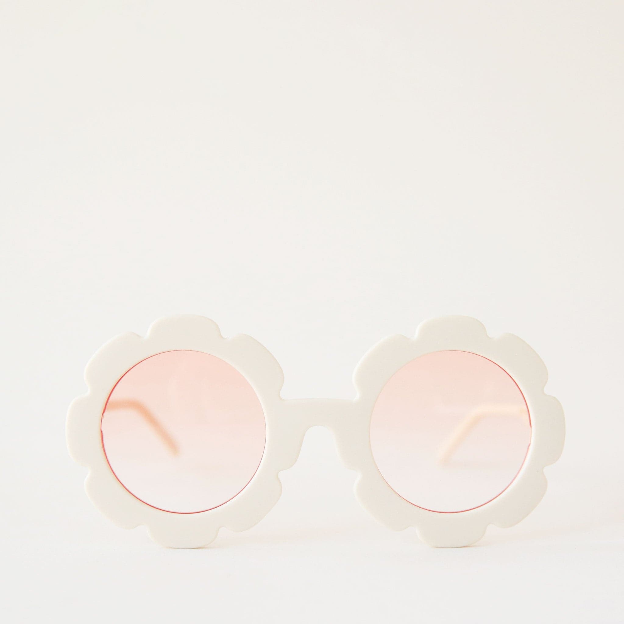 White flower shaped sunglasses with light pink lenses.
